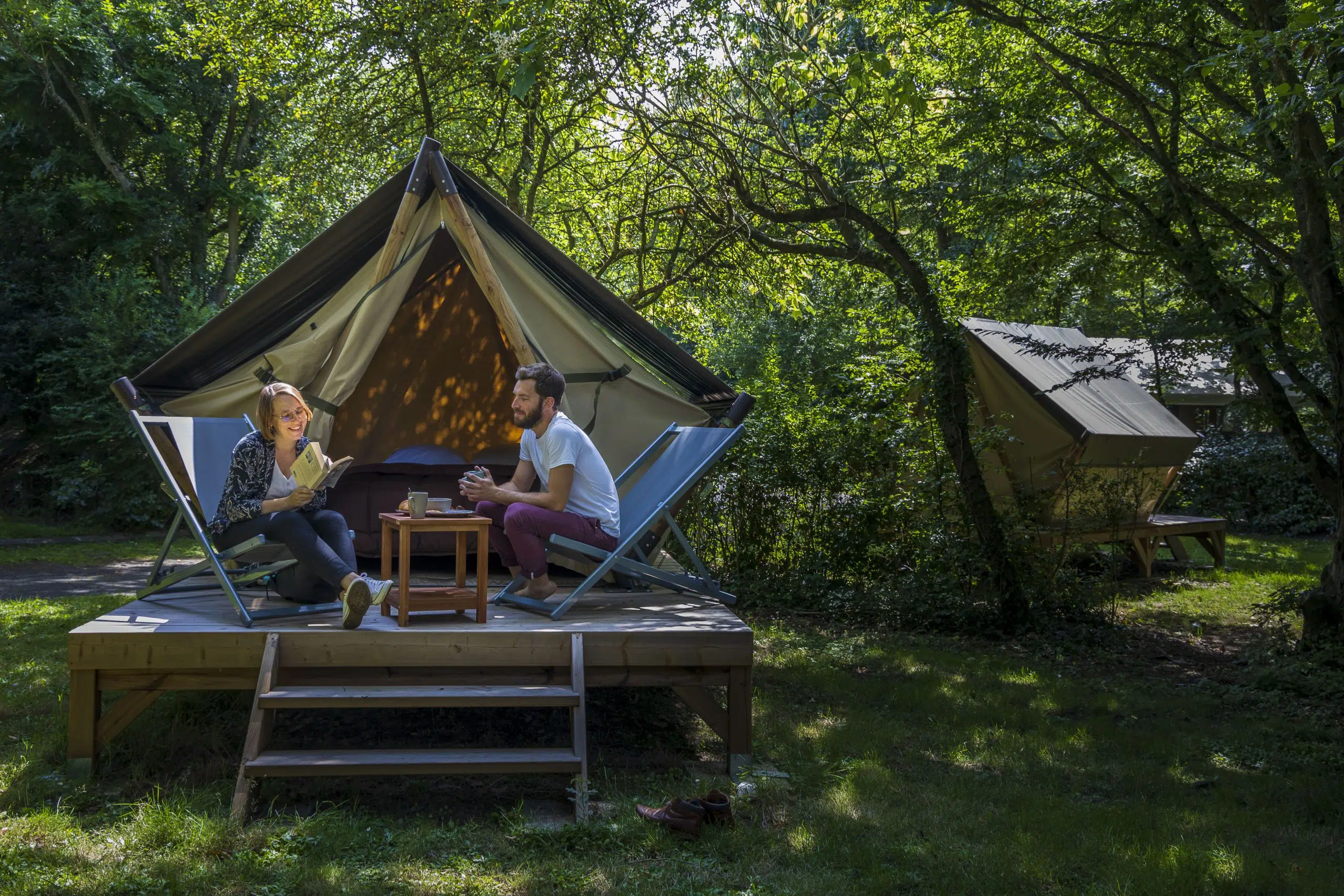 Une couple sur la terrasse des tentes bivouac au camping de Coulvée
