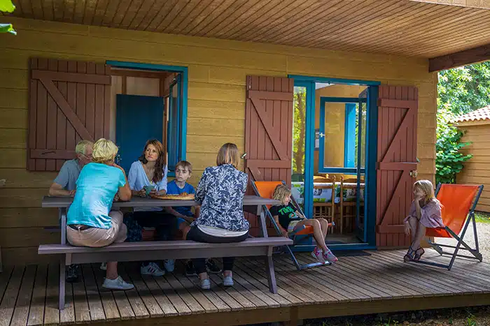 Famille sur la terrasse d'un chalet au Camping de Coulvée